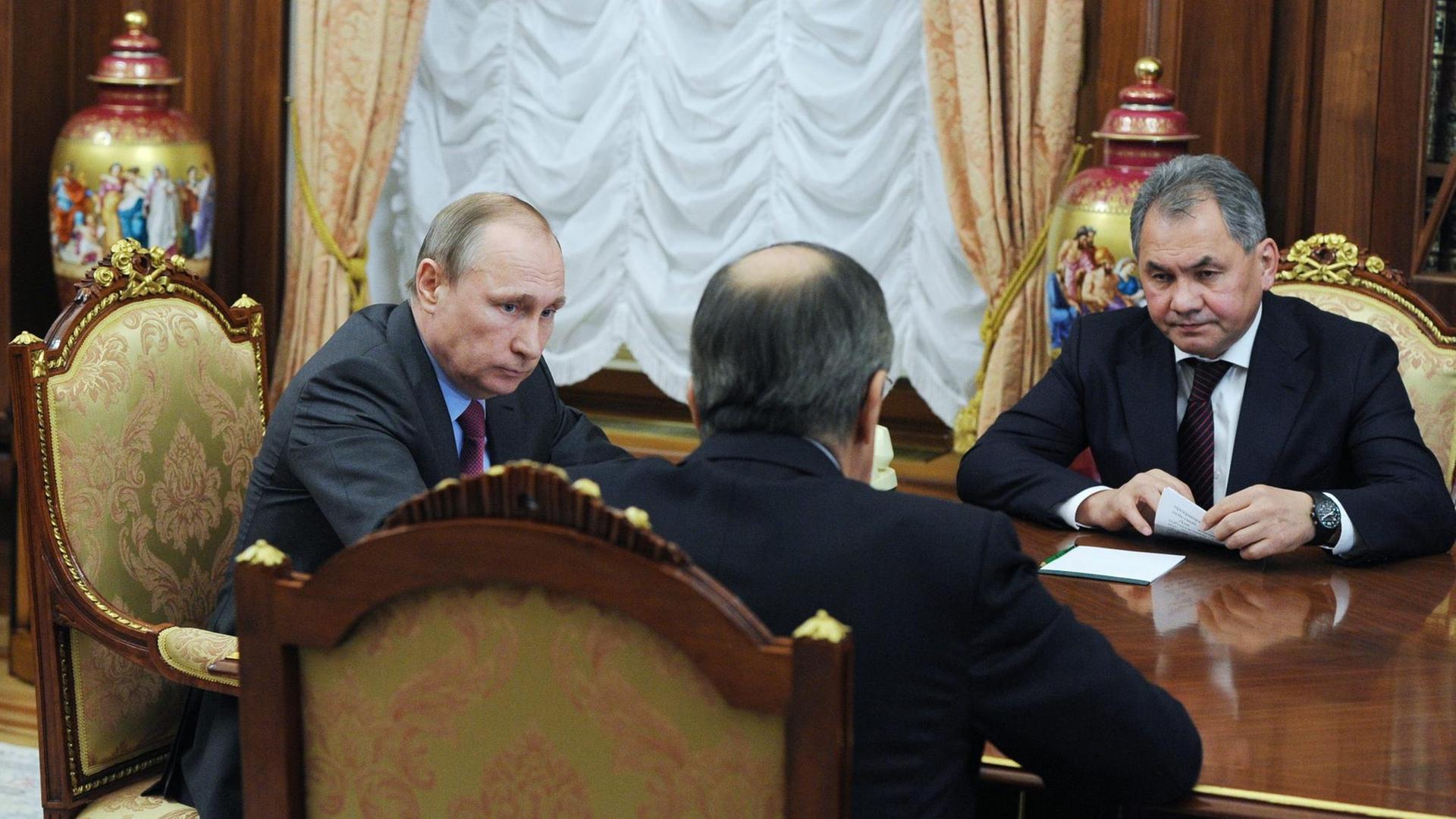 Russlands Präsident Wladimir Putin im Gespräch mit Außenminister Sergej Lawrow (m.) und Verteidigungsminister Sergej Shoygu (r.).