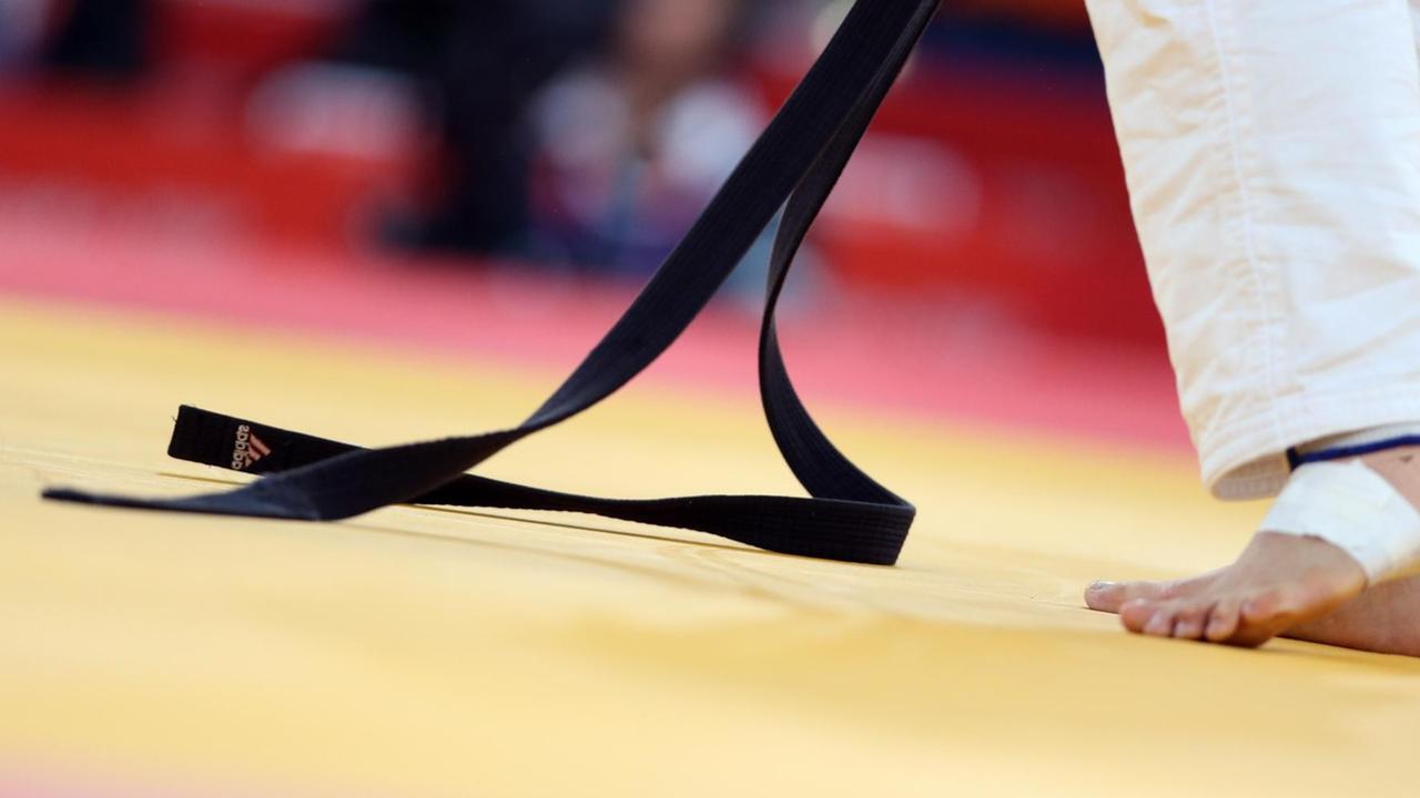 Ein schwarzer Judogürtel liegt zum Teil auf dem Boden
