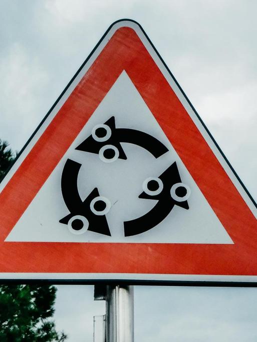 Ein Hinweisschild für einen Kreisverkehr, das mit Aufklebern verfremdet wurde.