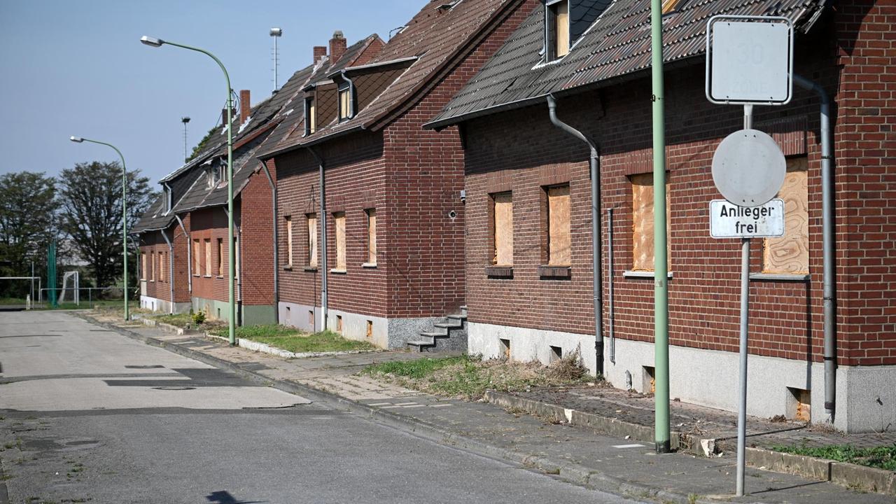 Eine Straßenzeile mit Häusern in Morschenich, deren Fenster mit Holzbrettern vernagelt sind. 
