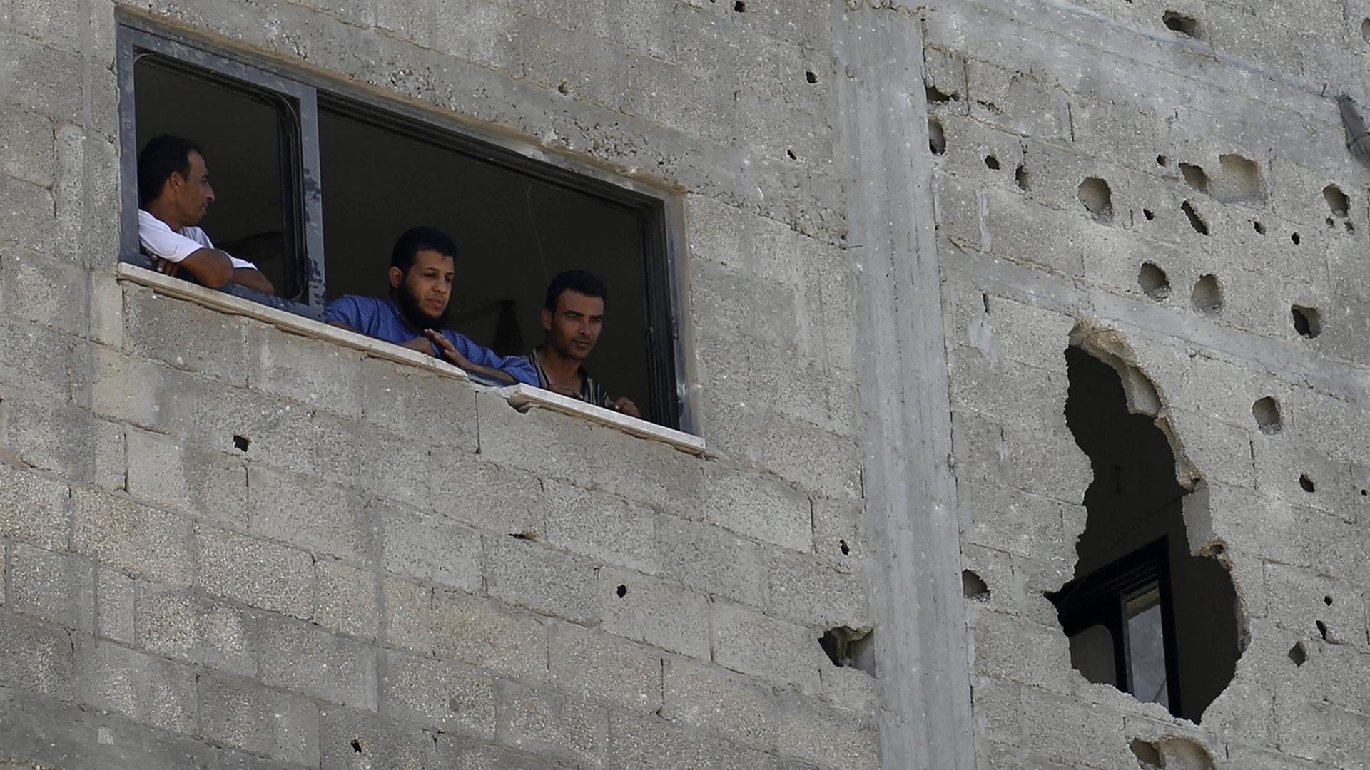 Palästinenser im Gaza-Streifen schauen aus ihrem zerstörten Haus.