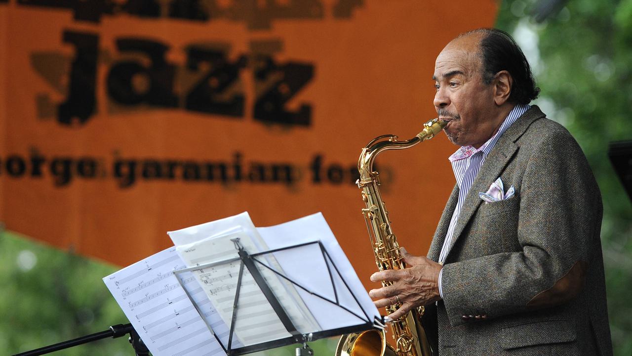 Benny Golson steht auf einer Bühne und spielt Saxophon