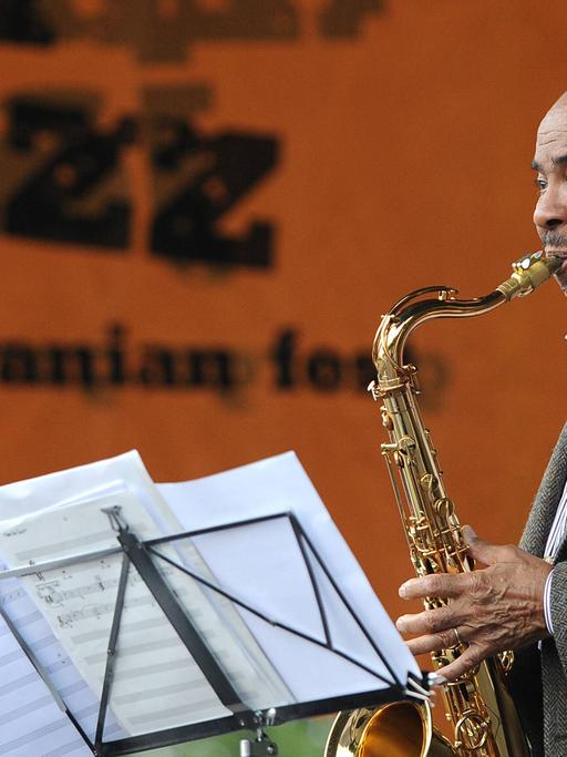 Benny Golson steht auf einer Bühne und spielt Saxophon