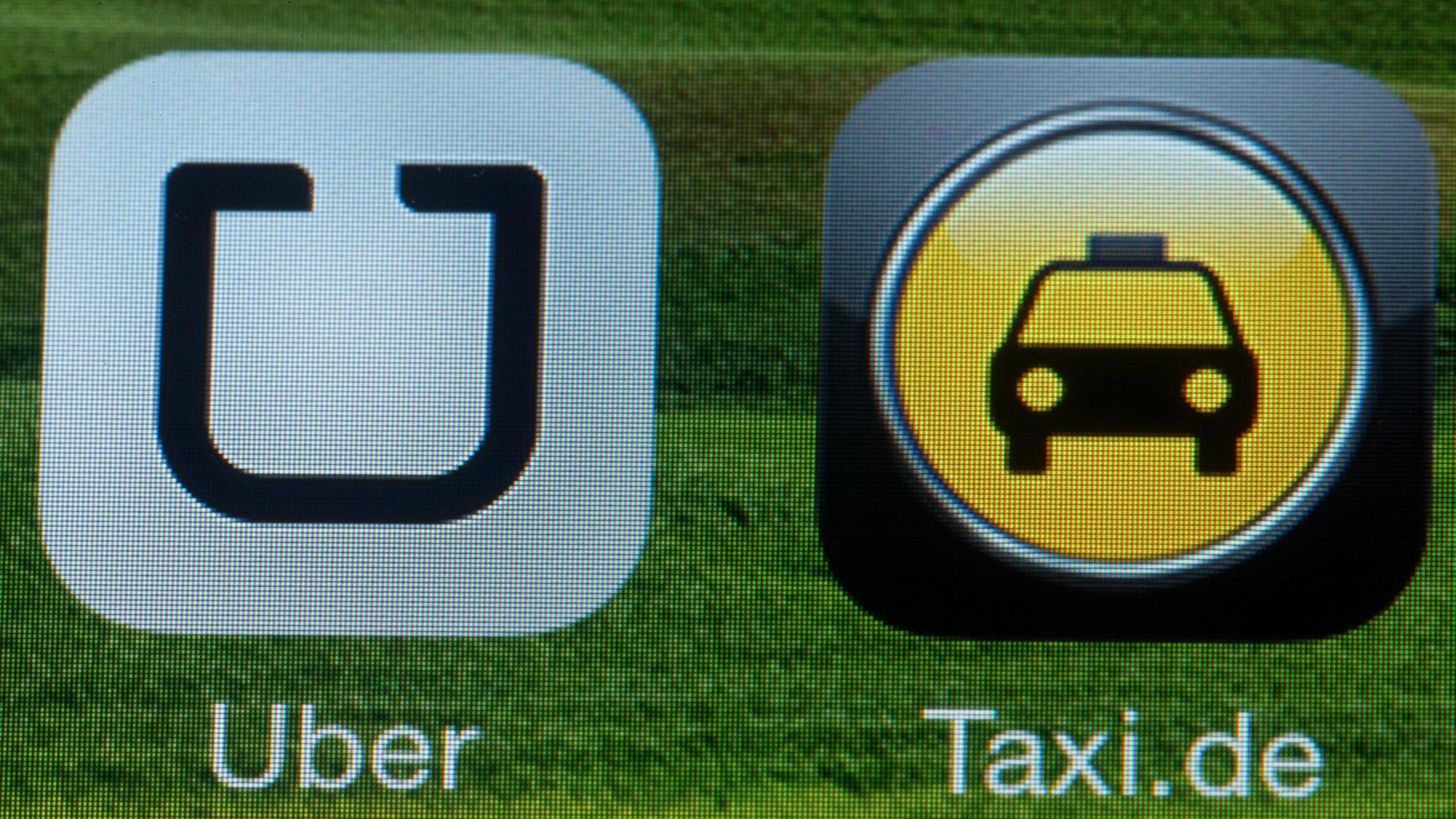 Die Handy-App "Uber" auf einem Smartphone neben dem Logo der Taxi-Vermittlung, Aufnahme vom September 2014