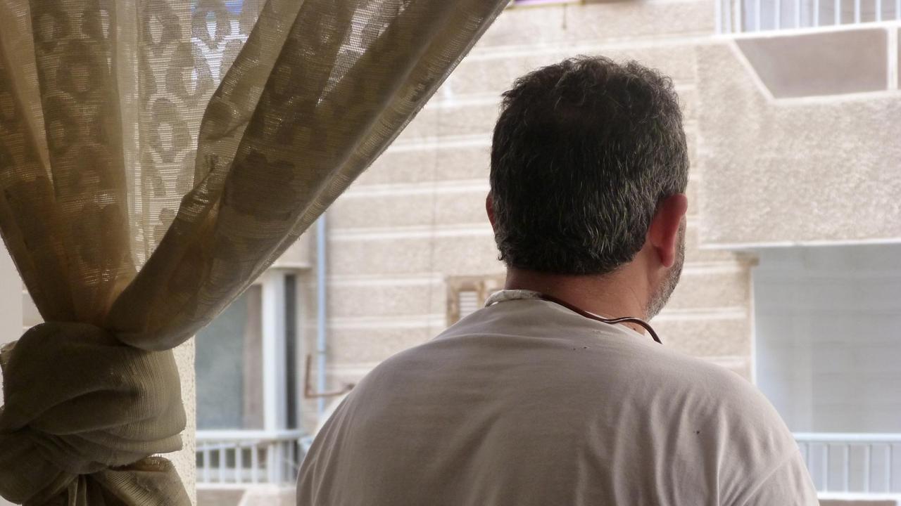 Farbfoto eines Mannes von hinten vor einem Fenster, der Syrer Abu Nimr, Flüchtling in Alexandria, Ägypten
