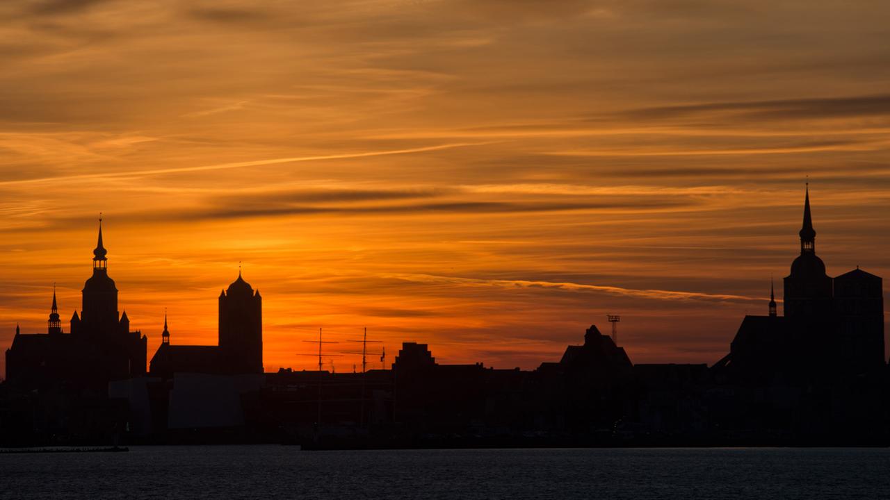 Farbenprächtig zeigt sich am 30.12.2013 der Himmel über der Silhouette der Hansestadt Stralsund, aufgenommen von der Insel Rügen aus.