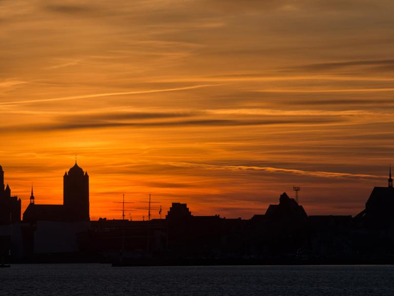 Farbenprächtig zeigt sich am 30.12.2013 der Himmel über der Silhouette der Hansestadt Stralsund, aufgenommen von der Insel Rügen aus.