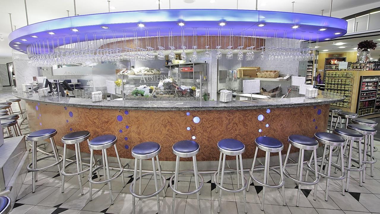 Eine Bar mit lila Sitzpolstern und Gläsern unterm Thekendach