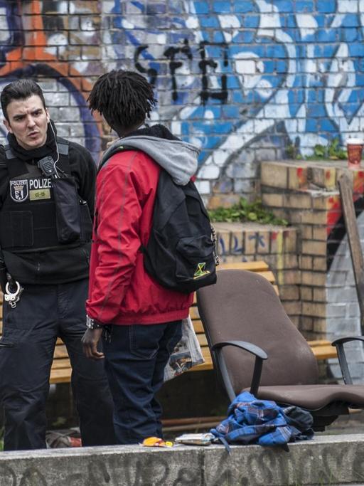 Die Grünanlage im Stadtteil Kreuzberg ist Treffpunkt für Drogendealer und Konsumenten. Polizisten kontrollieren einen Mann vor einer Mauer mit Graffitis