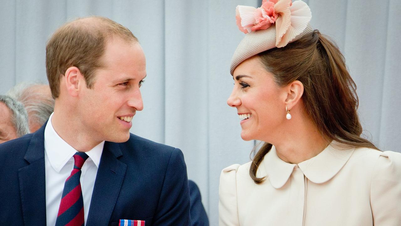 Prinz William und Kate, festlich gekleidet, schauen sich lächelnd in die Augen.