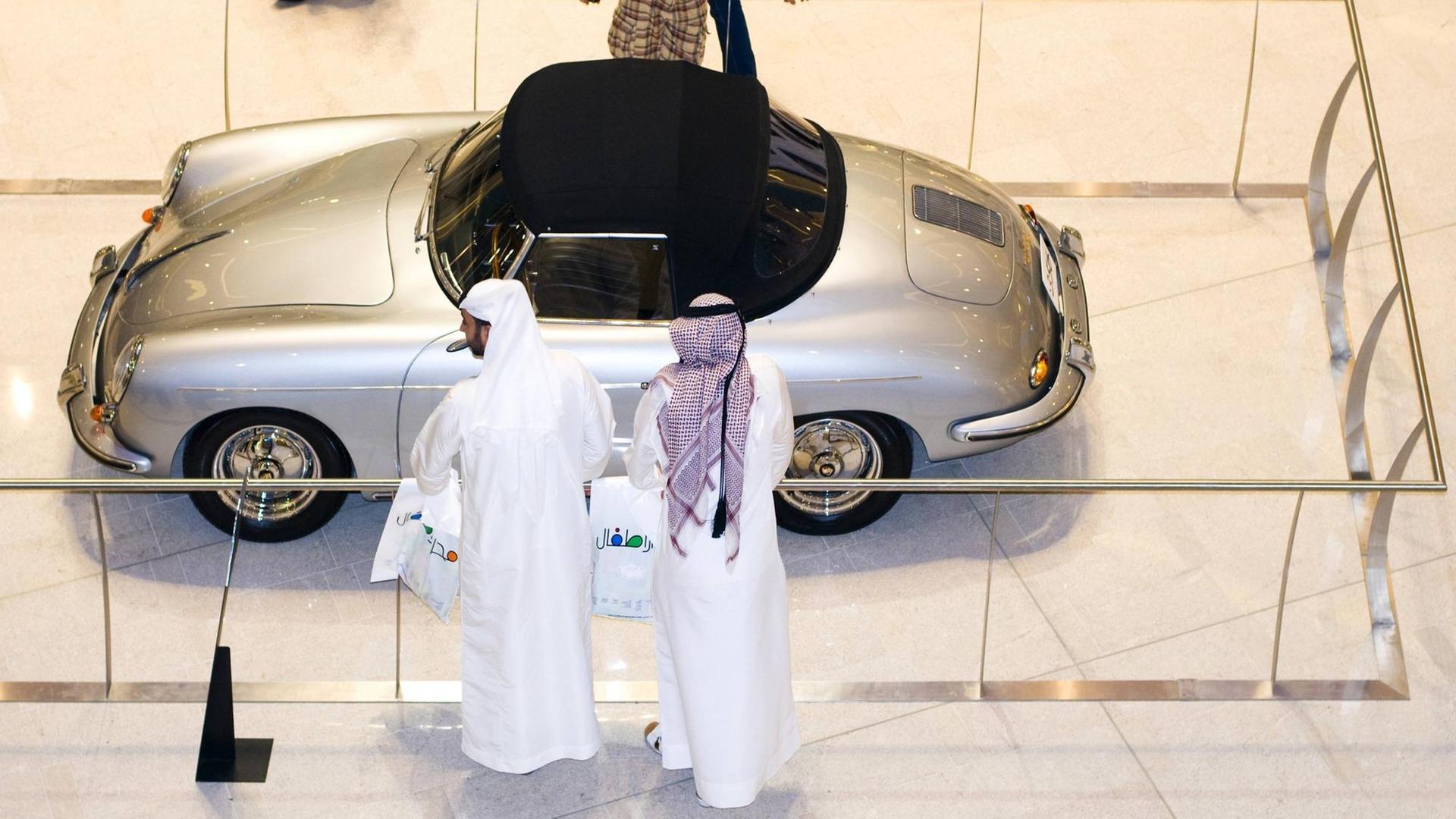Zwei Scheichs vor einem alten Porsche in einem Einkaufszentrum in Dubai