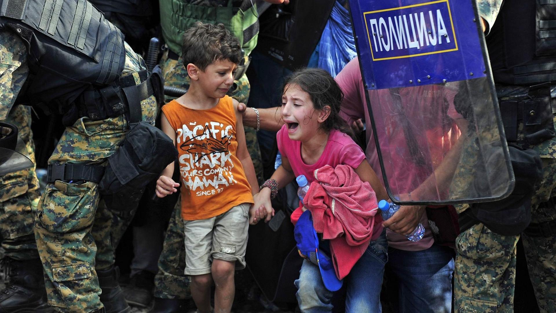 Zwei verletzte und weindende Kinder zwischen Polizisten an der mazedonischen Grenze zu Griechenland
