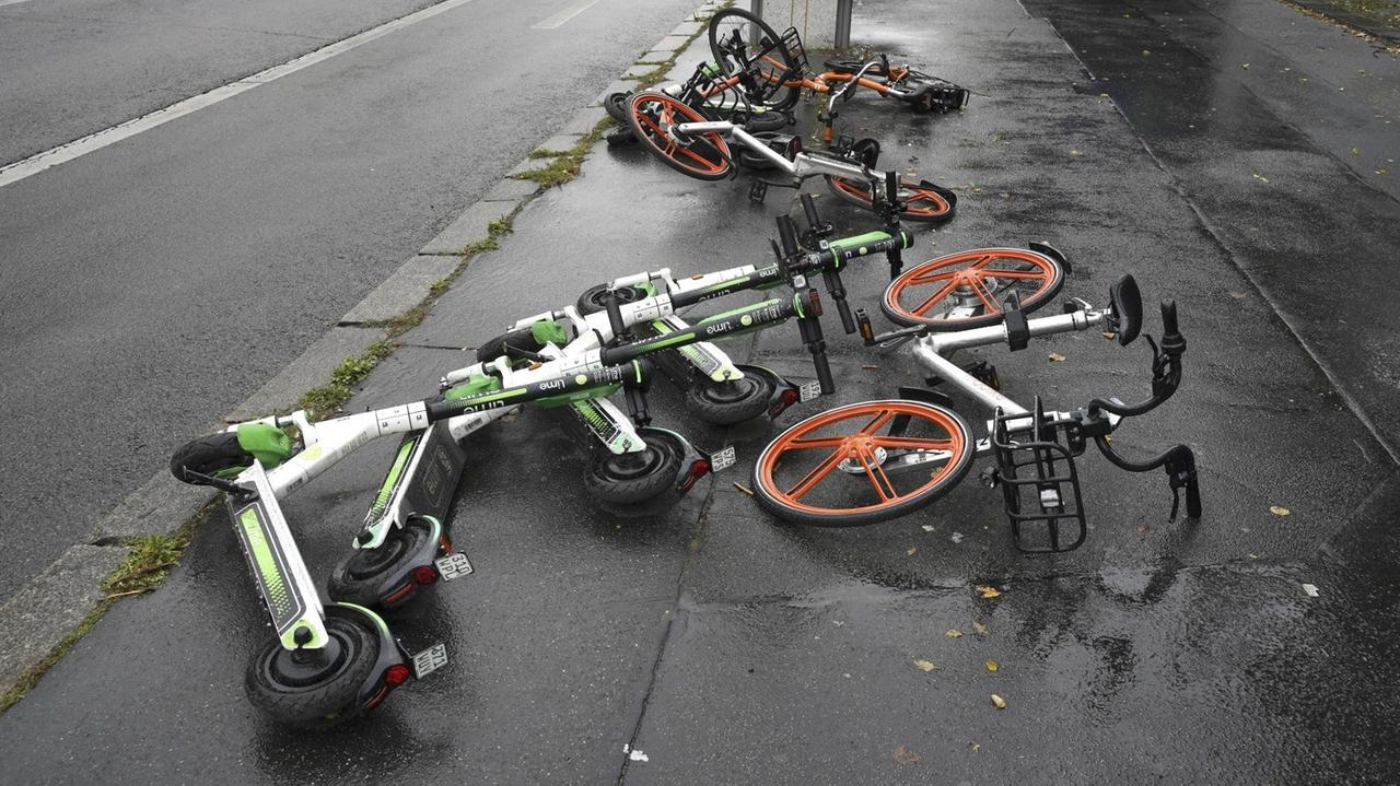 Auf einer Straße in Berlin liegen mehrere umgekippte Elektroroller und Leihräder.