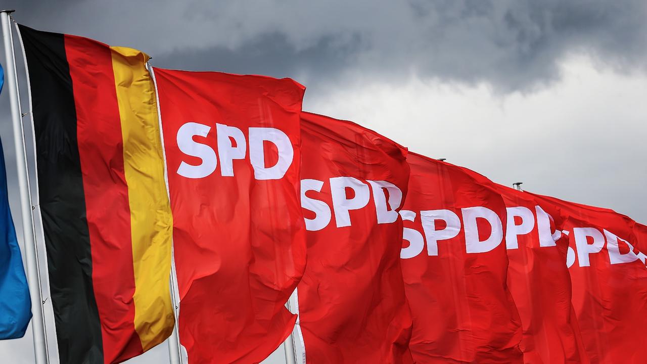 SPD-Fahnen und eine Deutschland-Flagge wehen am 13.04.2013 vor dunklen Wolken auf dem Messegelände in Augsburg (Bayern). Am 14.04.2013 findet in Augsburg ein eintägiger Bundesparteitag der Sozialdemokraten statt. Foto: Hannibal/dpa