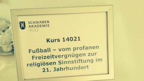 Ein Aufsteller-Schild der Schwaben Akademie mit der Aufschrift "Fußball - Vom profanen Freizeitvergnügen zur religiösen Sinnstiftung im 21. Jahrhundert"