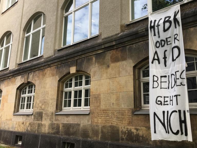 Aus dem ersten Stock des Bibliotheksgebäudes der HfBK Dresden hängt ein weißes Stoffbanner, auf das in schwarzer Schrift steht: "HfBK oder AfD - beides geht nicht".