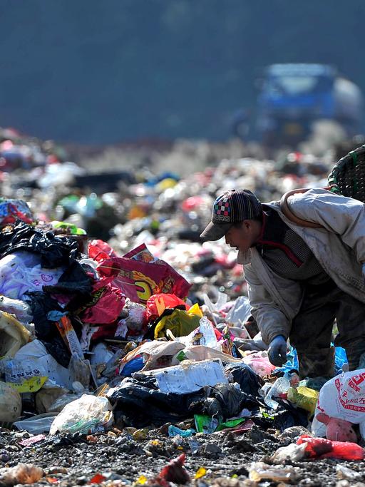 Ein Mann sucht auf einer chinesischen Müllhalde nach verwertbaren Abfällen, die er verkaufen kann.