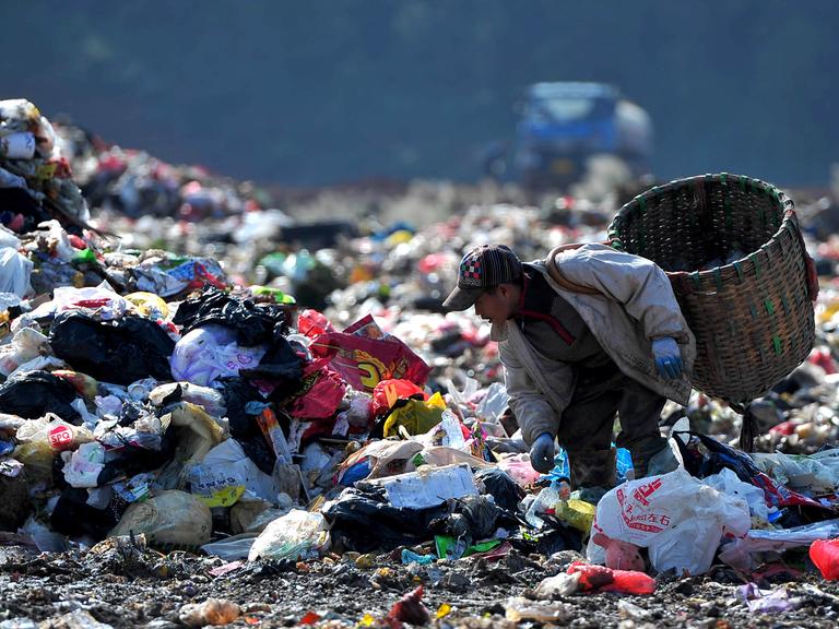 Ein Mann sucht auf einer chinesischen Müllhalde nach verwertbaren Abfällen, die er verkaufen kann.