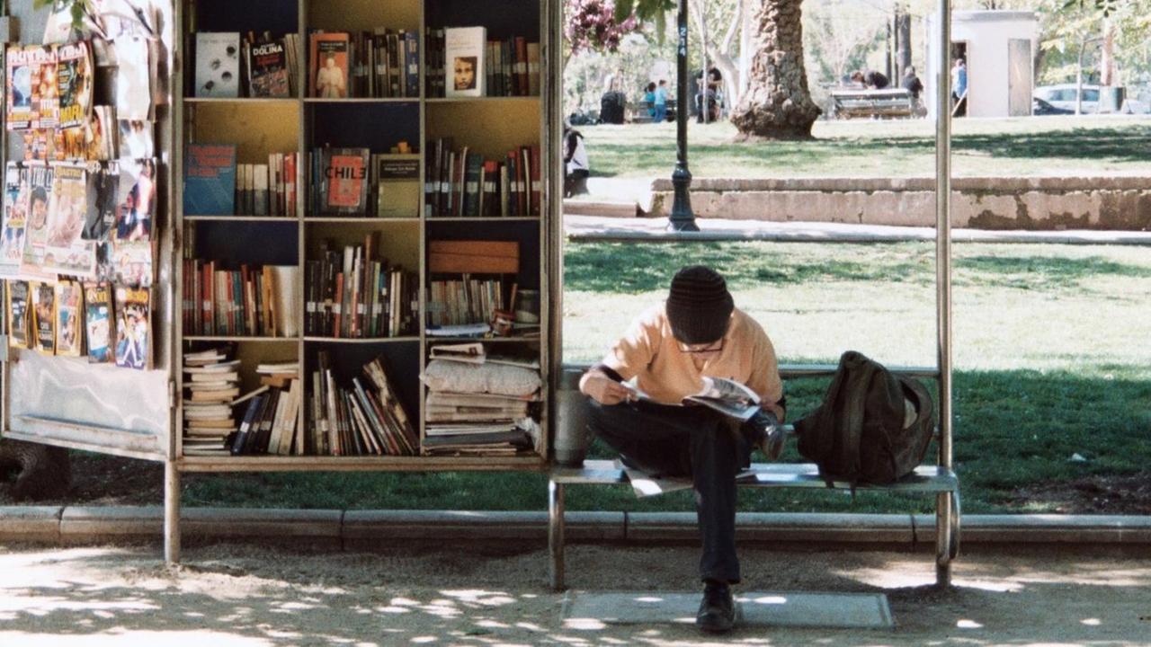 Ein Mann liest vor einem Bücherstand.