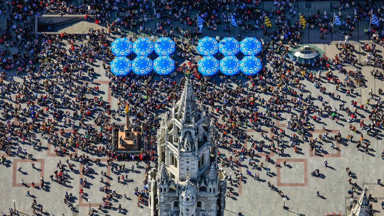 Luftbild vom Rathausturm am Marienplatz in München, vor dem die Touristen auf das Glockenspiel warten