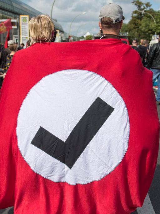 Zwei Demonstranten tragen das Logo von "Hooligans Gegen Satzbau" bei einer Demo gegen den rechtsextremen Hess-Gedenkmarsch in Berlin.