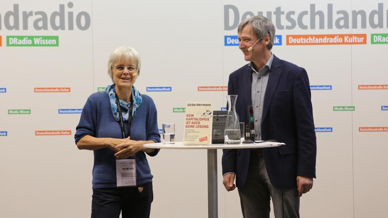 Sie sehen die Buchautorin Ulrike Herrmann und den Deutschlandfunk-Redakteur Georg Ehring.