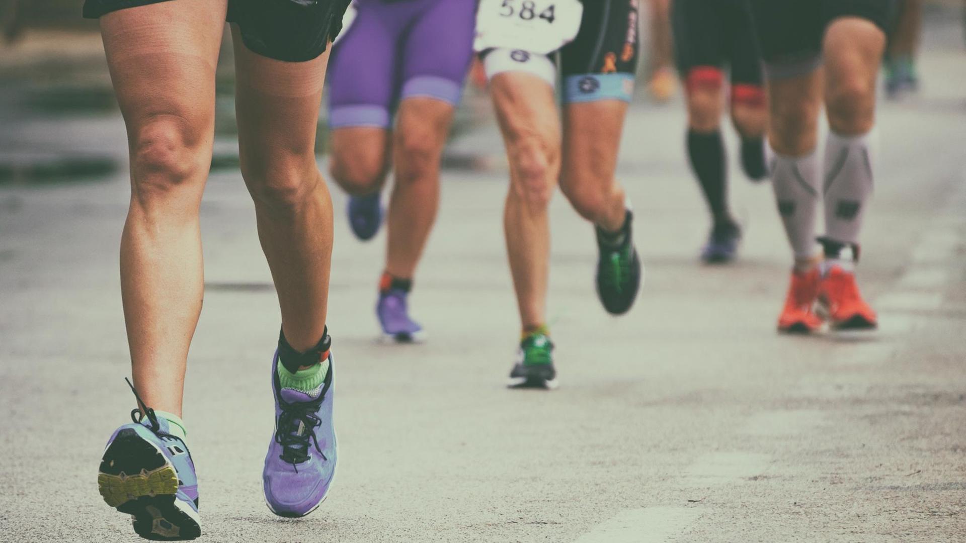 Die Beine einer Gruppe von Marathon-Läufern auf der Straße