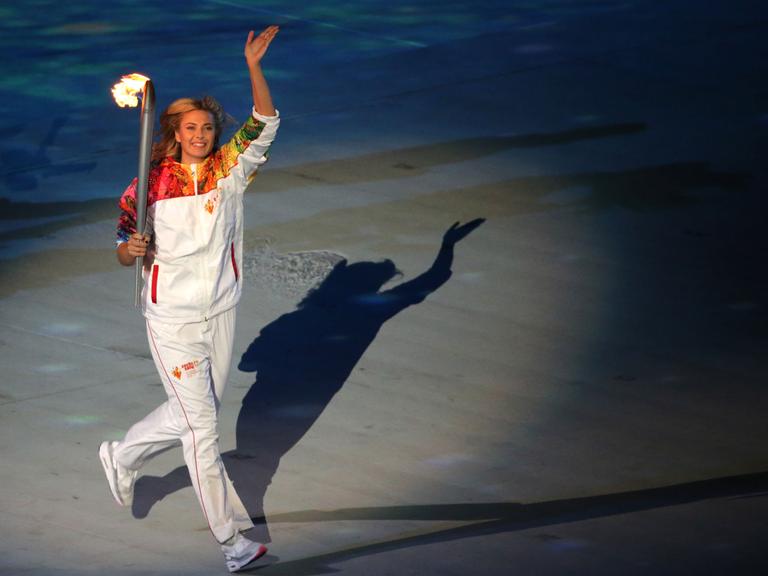 Die russische Tennisspielerin Maria Sharapova trägt bei der Eröffnungszeremonie in Sotschi die olympische Fackel.