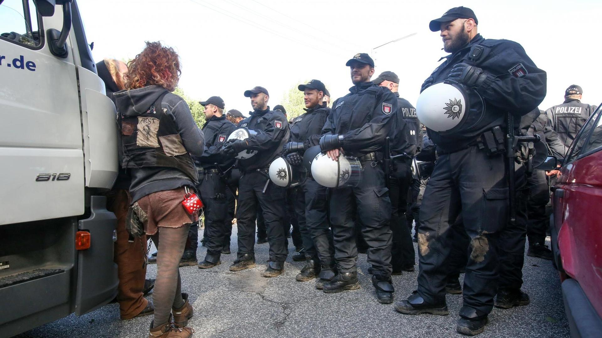 Uniformierte Polizisten stehen aufgereiht vor einem LKW, an dem ein Demonstrant lehnt