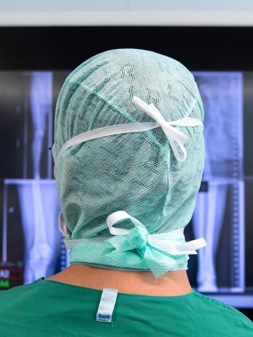 Ein Arzt schaut sich nach einer Knie-Operation in einem Operationssaal Röntgenbilder auf einem Monitor an.