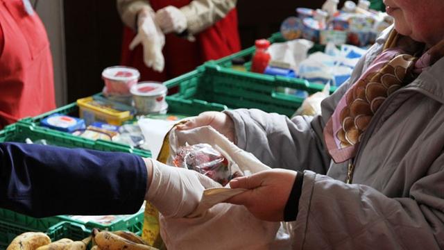 Eine Mitarbeiterin verteilt Obst an Bedürftige in der Lebensmittelausgabe "Laib und Seele" der Berliner Tafeln am 24.4.2014 in der Evangelischen Advents-Zachäus-Kirchengemeinde in Berlin.