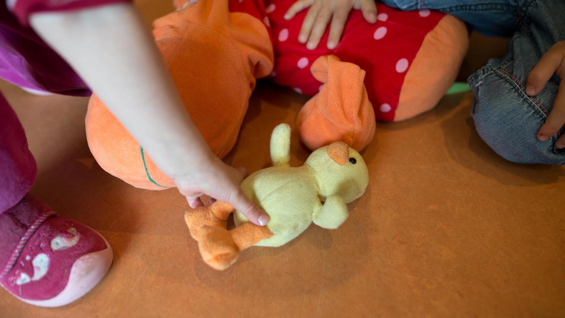 Ein Kind hält eine Plüschtierente in einer Kindertagesstätte in der Hand.