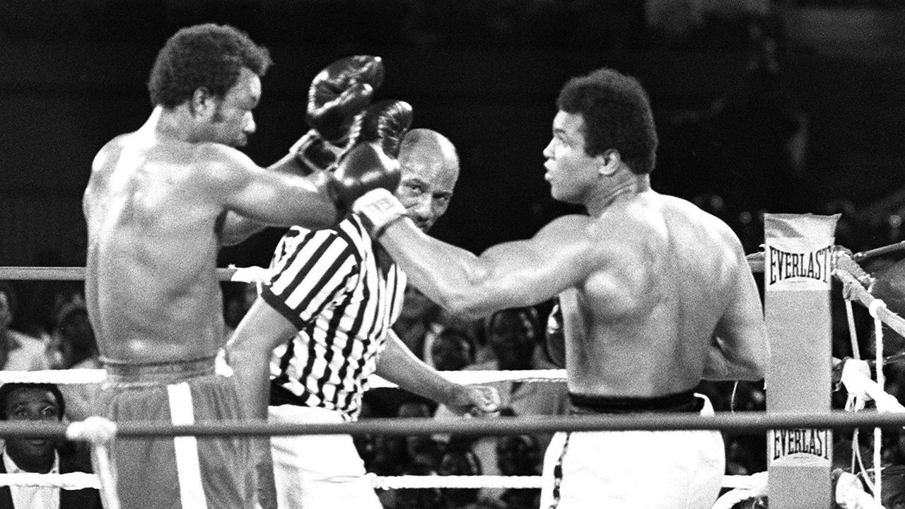 Muhammad Ali (r.) und George Foreman (l.) boxen am 30. Oktober 1974 in Kinshasa im Ring, im Hintergrund der Schiedsrichter. Schwarz-weiß-Foto.