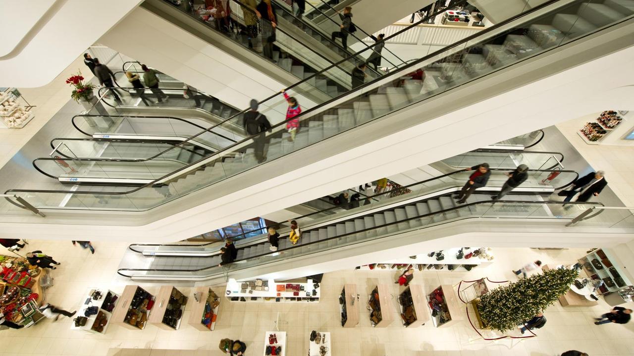 Menschen stehen am 21.11.2013 in Berlin auf Rolltreppen in einem Kaufhaus. 