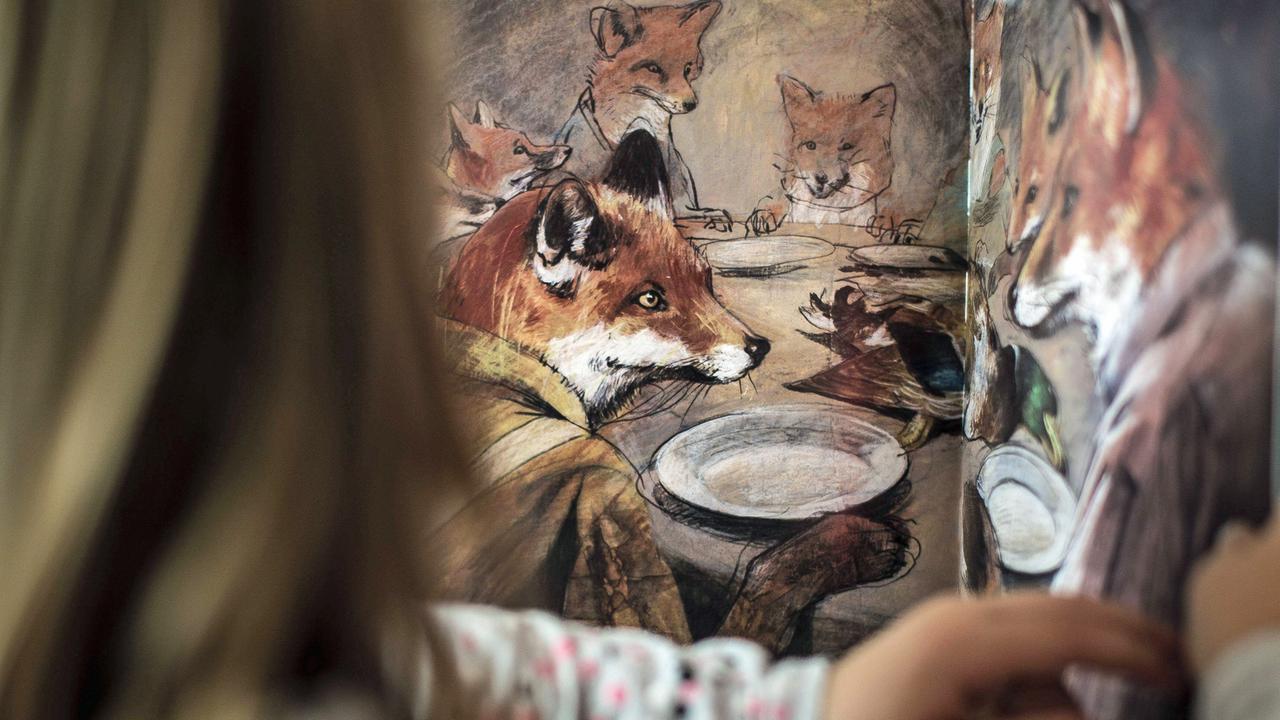 Ein Kind blättert in einem Bilderbuich mit Illustrationen von Jonas Lauströer.
