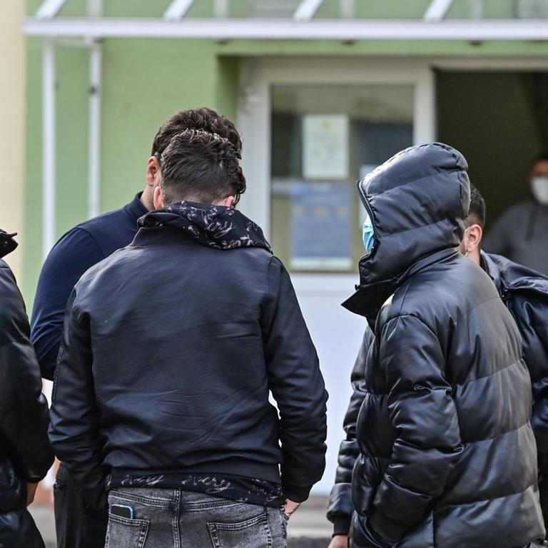 Flüchtlinge stehen auf dem Gelände einer Erstaufnahmeeinrichtung. 