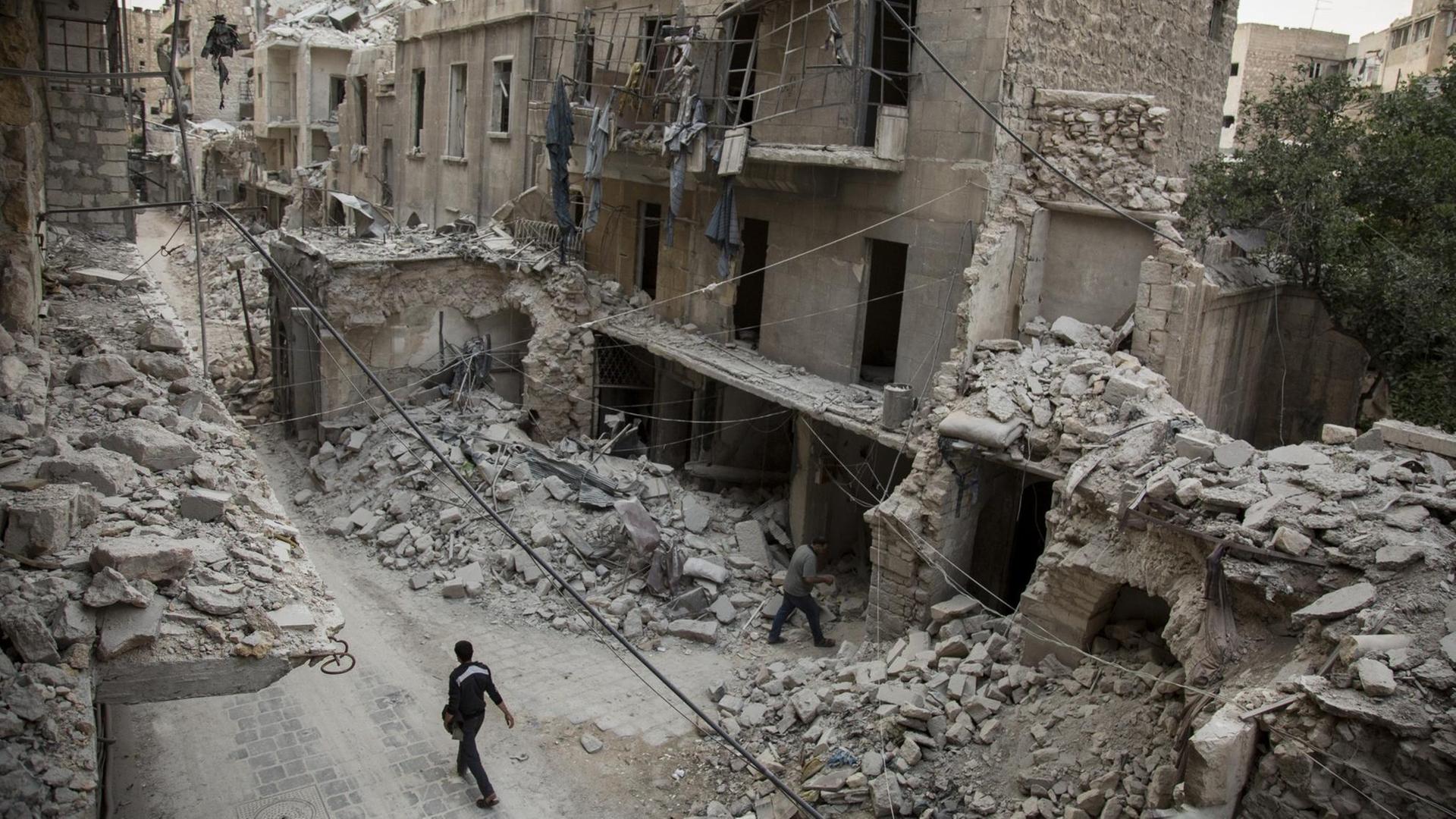 Ein Mann läuft durch eine Straße mit völlig zerstörten Häusern in Aleppo