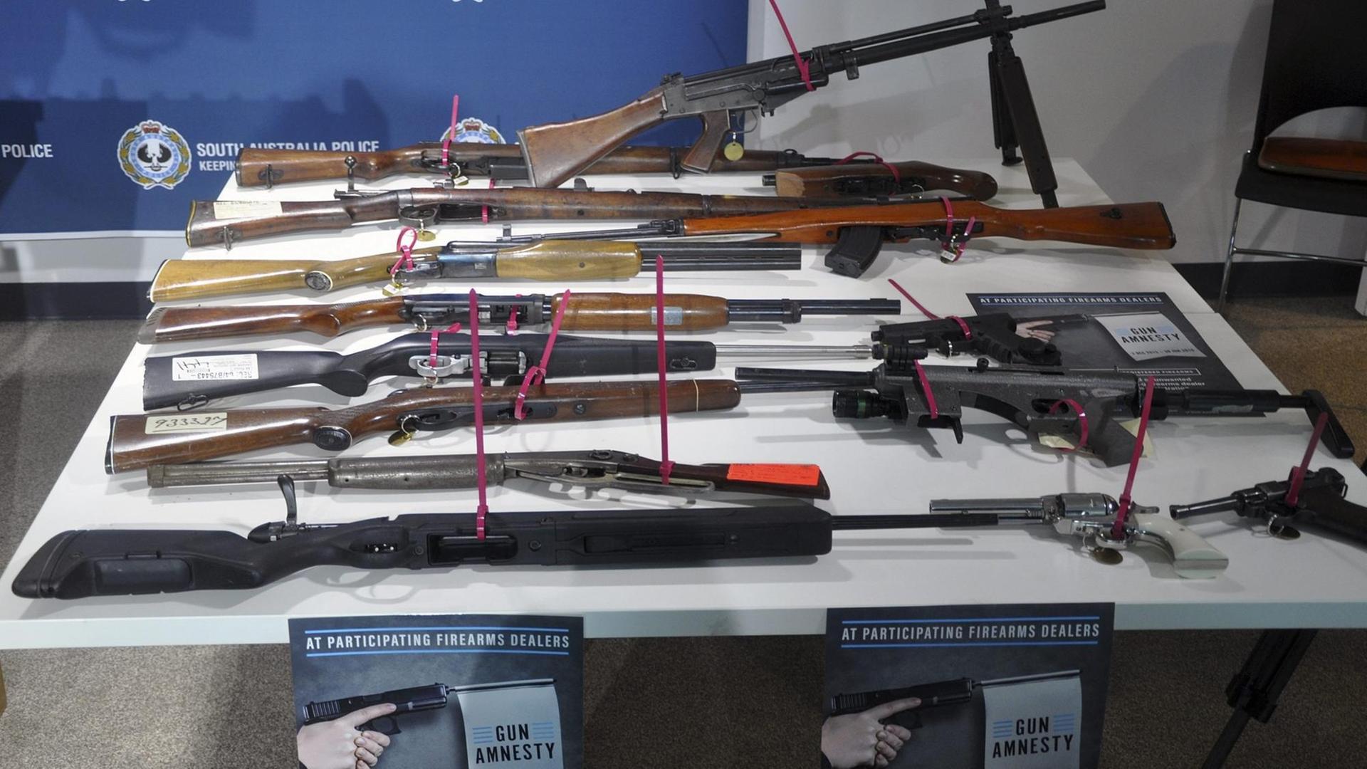Verschiedene Waffen sind mit Kabelbindern auf einem weißen Tisch befestigt. Verschiedene Waffen sind mit Kabelbindern auf einem weißen Tisch befestigt.