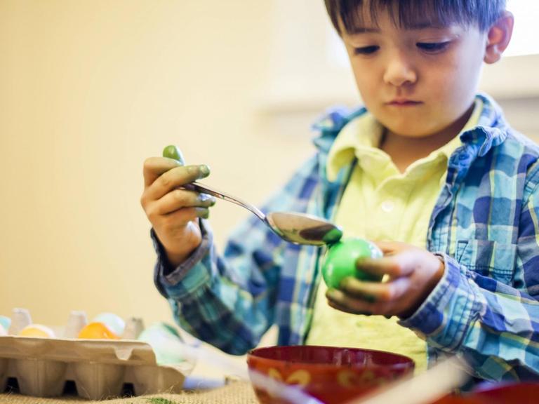 Ein vierjähriger Junge färbt ein Osterei (Symbolfoto).