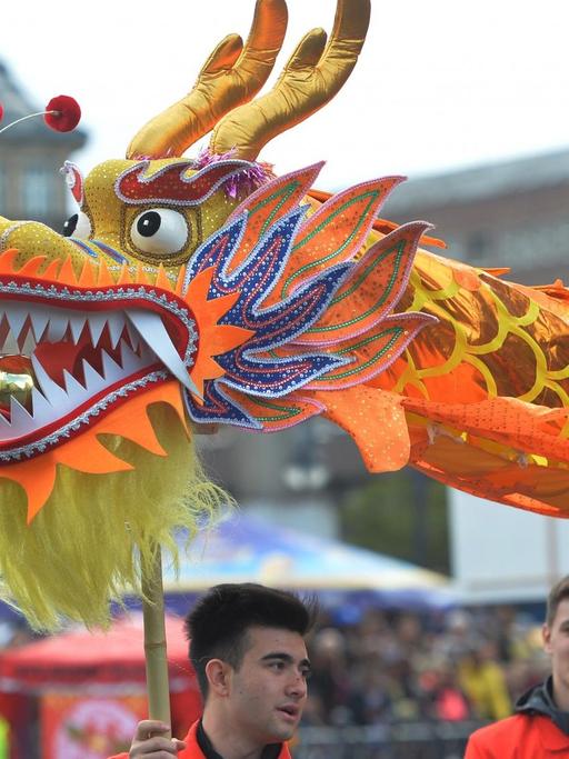 Mit einem asiatischen Papierdrachen nimmt eine Gruppe am 15.05.2016 in Berlin am Straßenumzug zum 21. Karneval der Kulturen teil.
