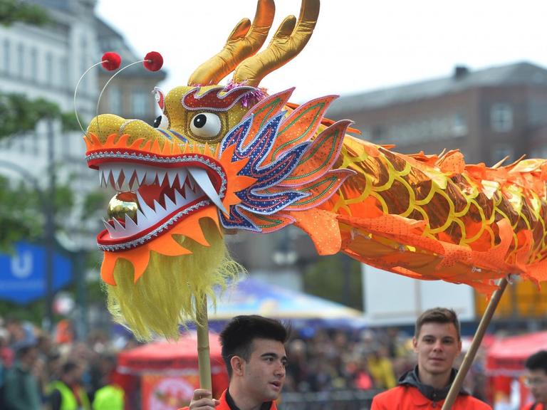 Mit einem asiatischen Papierdrachen nimmt eine Gruppe am 15.05.2016 in Berlin am Straßenumzug zum 21. Karneval der Kulturen teil.