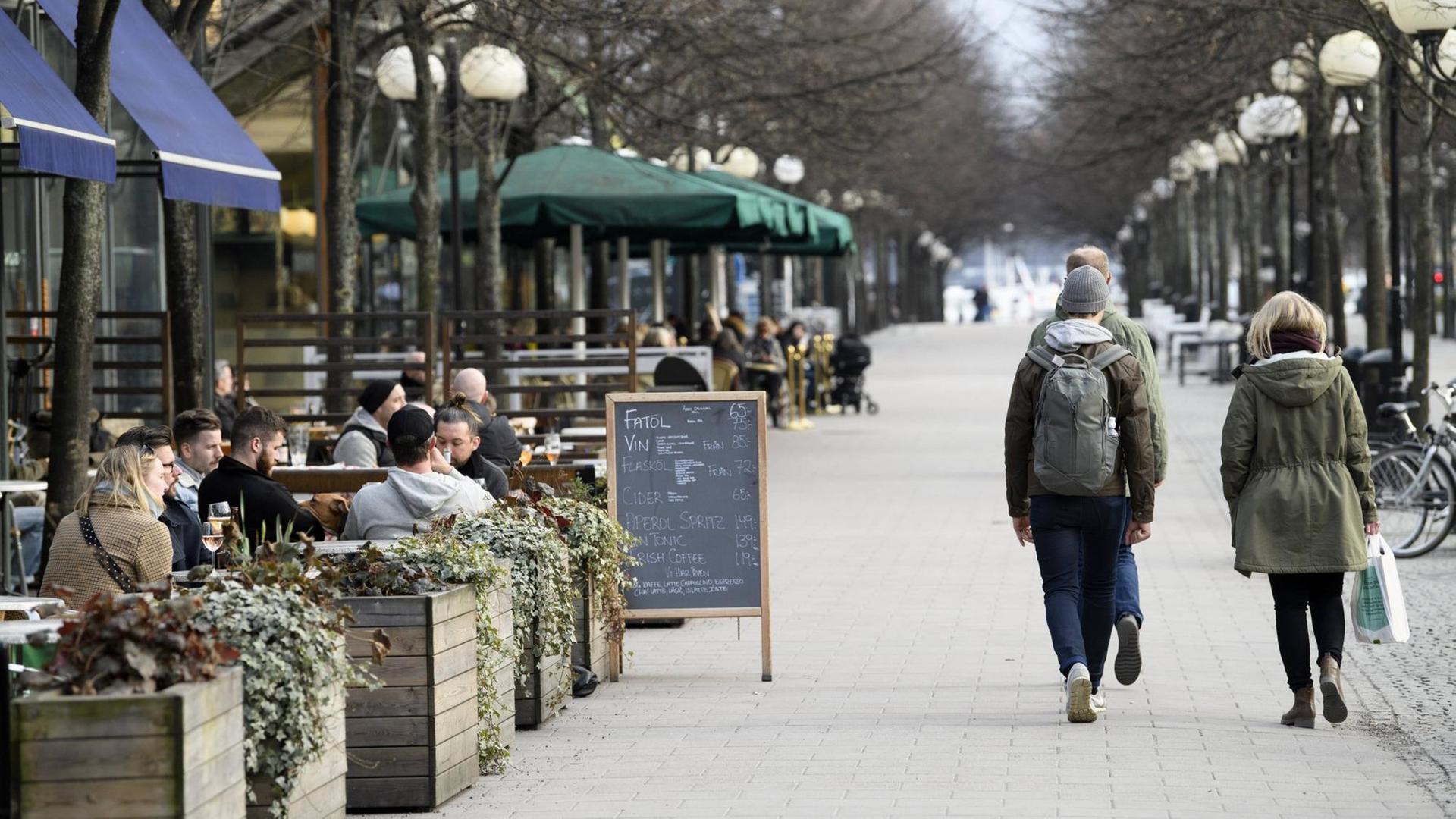 Promenade in Stockholm, über die an einem Nachmittag viele Menschen laufen, auch die Straßencafes sind gut gefüllt.