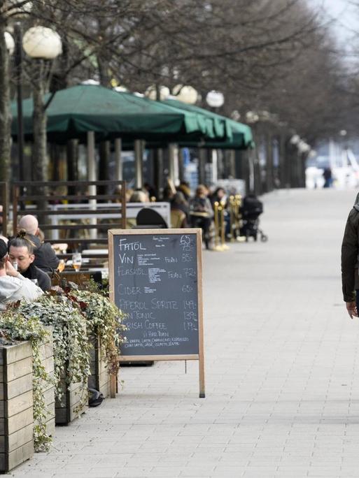 Promenade in Stockholm, über die an einem Nachmittag viele Menschen laufen, auch die Straßencafes sind gut gefüllt.