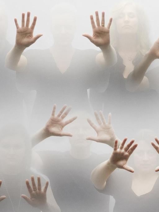 Die Chormitglieder stehen mitten im Nebel, vor allem ihre ausgespreizten Hände treten hervor.
