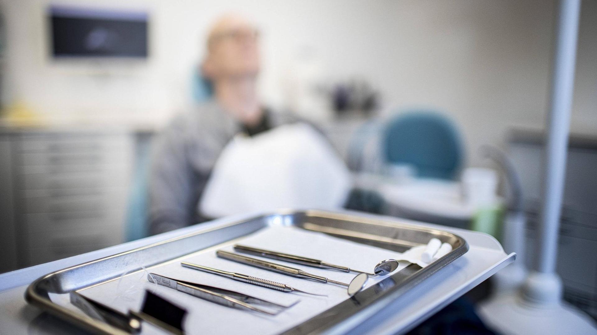 Ein Mann sitzt in einer Praxis auf einem Zahnarztstuhl.