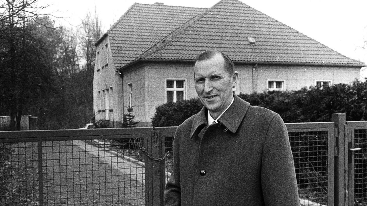 Ein Schwarz-Weiß-Bild von 1990. Uwe Holmer steht vor seinem Wohnhaus, wo er dem Ehepaar Honecker Asyl gewährte.