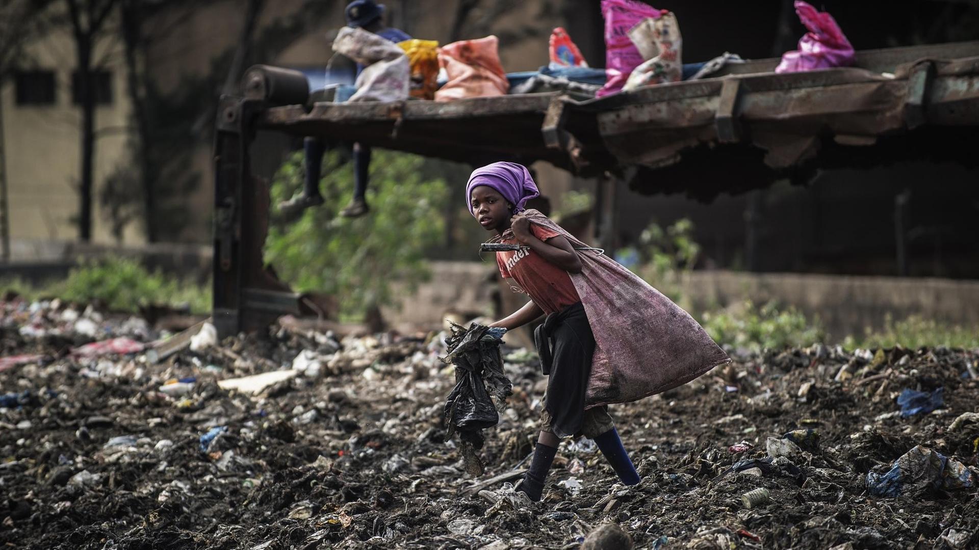 Ein Mädchen läuft in Maputo in Mosambik über eine Müllhalde und sammelt noch verwertbaren Abfall.