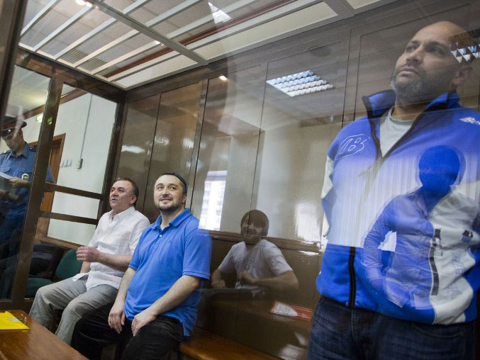 Ein Archivfoto vom 04.06.2013 zeigt drei Angeklagte im Fall des Mordes an der russischen Investigativ-Journalistin Anna Politkowskaja hinter einer Glasscheibe im Gerichtssaal in Moskau.