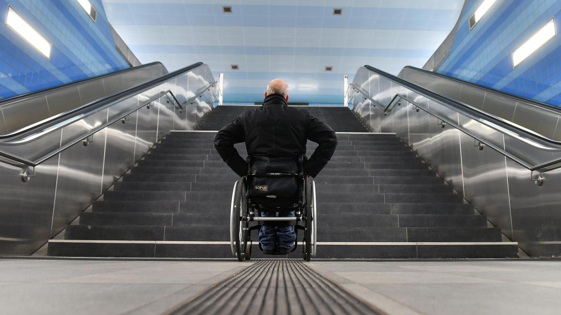 Ein Mann im Roll-Stuhl steht vor einer Treppe und kommt nicht weiter