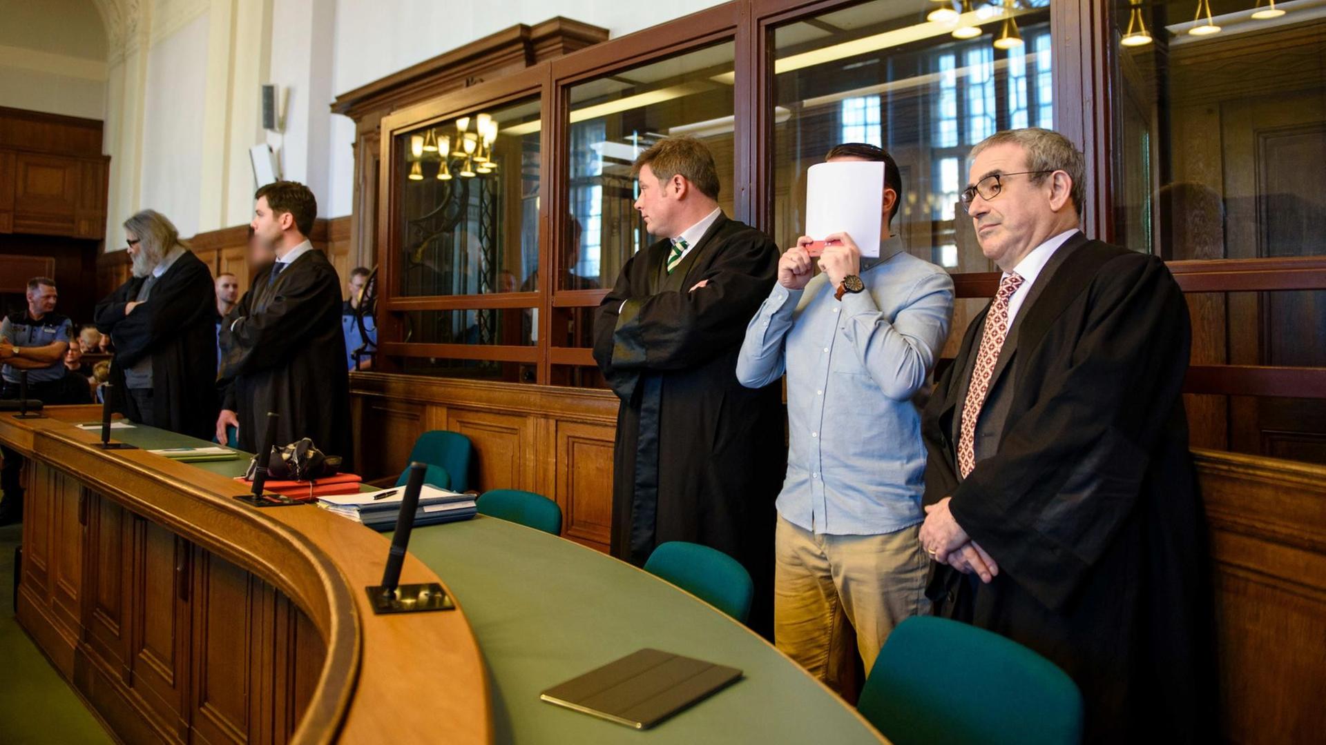 Die Angeklagte Hamdi H. und Marvin N. stehen am 27.02.2017 in Berlin in einem Gerichtssaal des Landgerichtes Berlin zwischen ihren Anwälten, Hamdi H. hält sich eine Akte vor das Gesicht. 